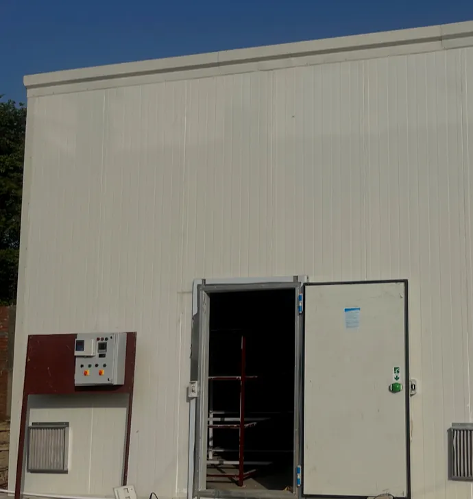 A finished MushroomWale PPGL PUF room: insulated door open on its racks, controller panel beside it