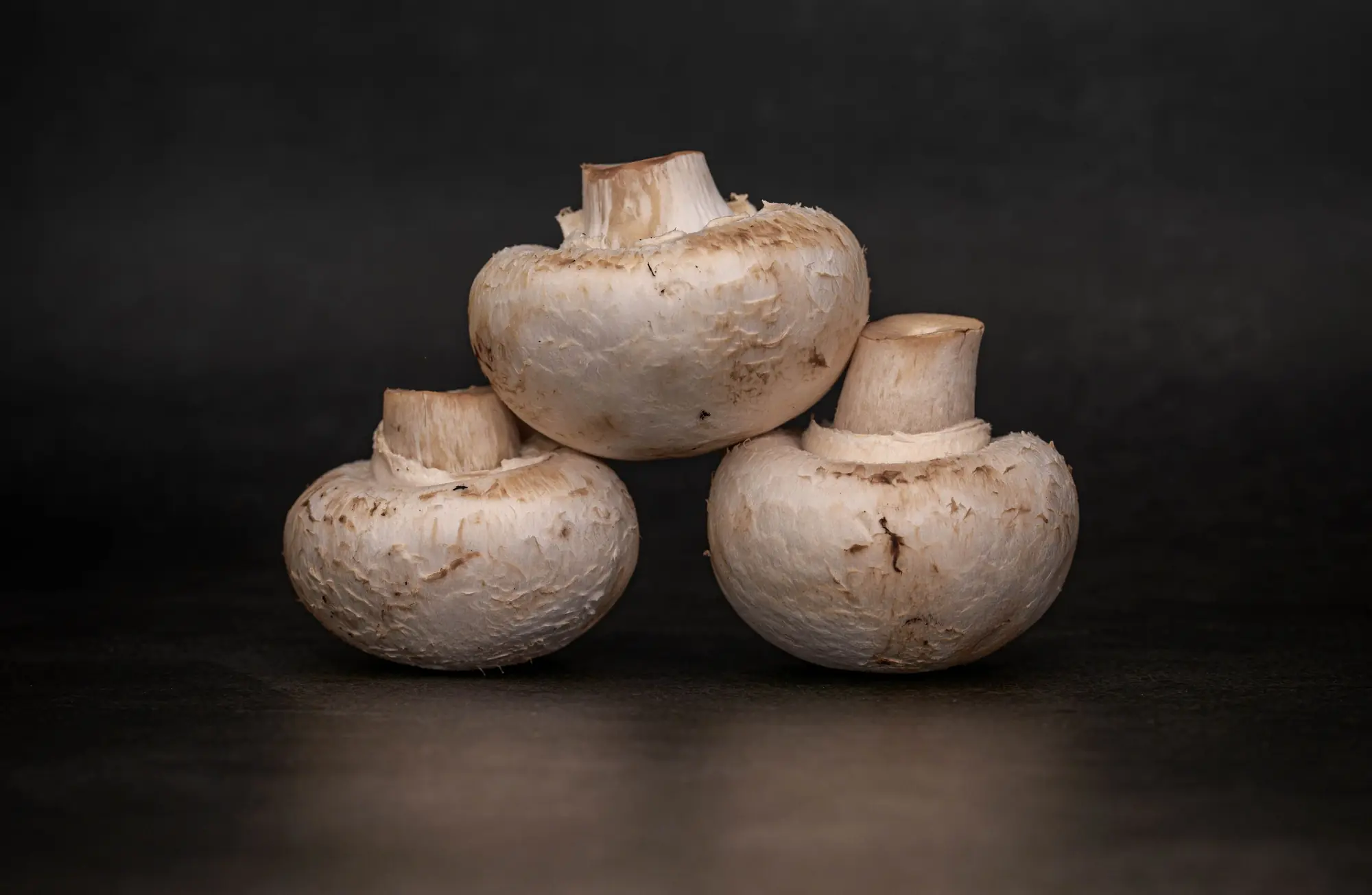 Fresh white button mushrooms on a dark table